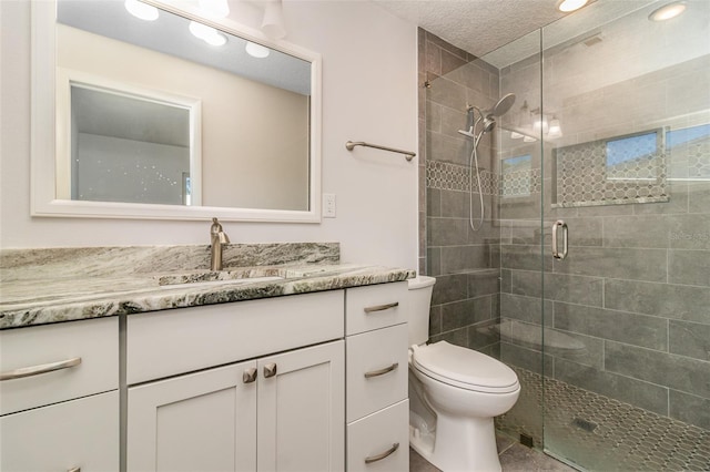 bathroom featuring a shower with shower door, a textured ceiling, toilet, tile patterned flooring, and vanity