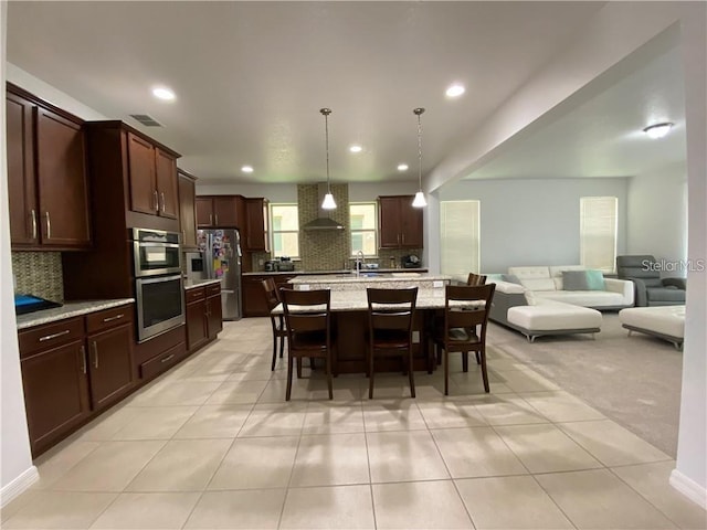 kitchen featuring backsplash, wall chimney exhaust hood, light tile floors, and stainless steel appliances