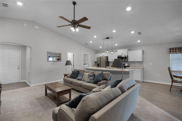 living room featuring high vaulted ceiling, ceiling fan, sink, and light hardwood / wood-style flooring