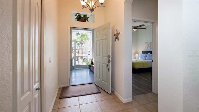 tiled entrance foyer featuring ceiling fan with notable chandelier