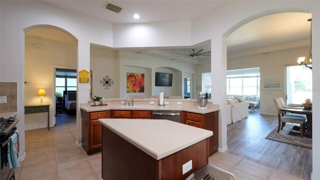 kitchen featuring a kitchen island, appliances with stainless steel finishes, light hardwood / wood-style flooring, ceiling fan with notable chandelier, and sink