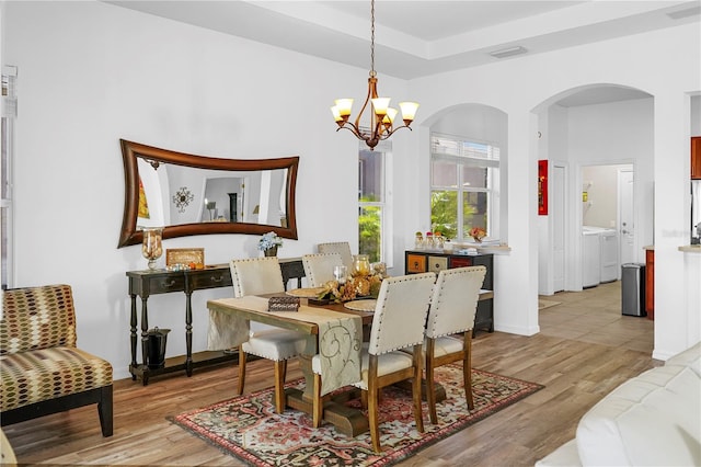 dining room featuring light hardwood / wood-style flooring, a notable chandelier, and separate washer and dryer