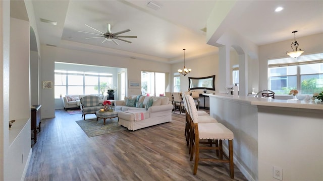 living room with dark hardwood / wood-style floors and ceiling fan with notable chandelier