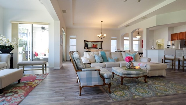 living room featuring hardwood / wood-style flooring, a tray ceiling, and ceiling fan with notable chandelier