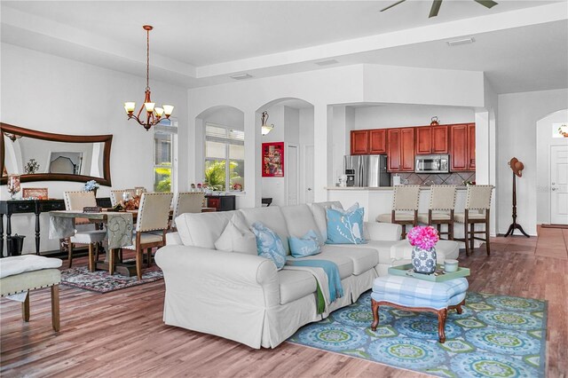 living room featuring hardwood / wood-style flooring and ceiling fan with notable chandelier