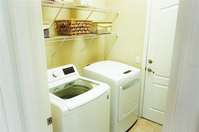 clothes washing area with washer and clothes dryer and light tile patterned floors