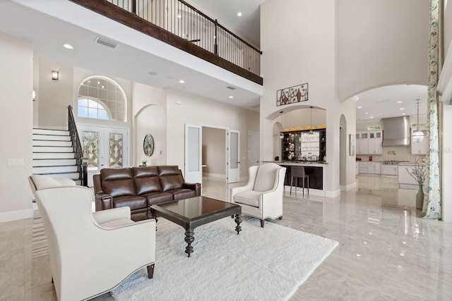 tiled living room with french doors and a towering ceiling