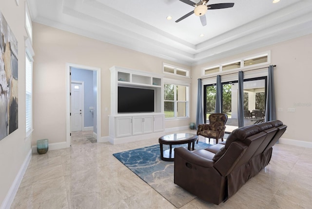 tiled living room featuring ornamental molding, ceiling fan, and a tray ceiling