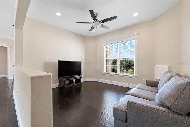 living room featuring dark wood-type flooring and ceiling fan