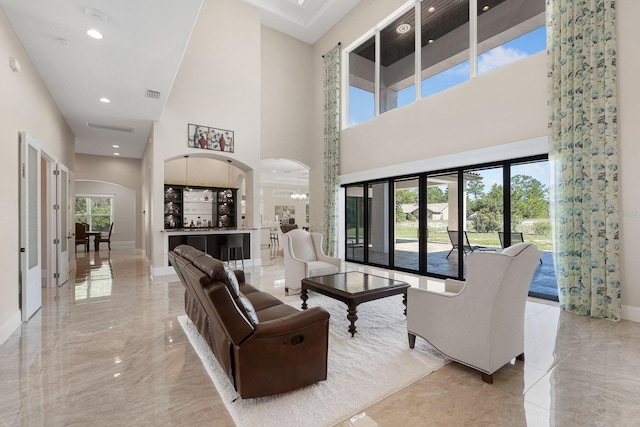 tiled living room featuring a wealth of natural light and a towering ceiling