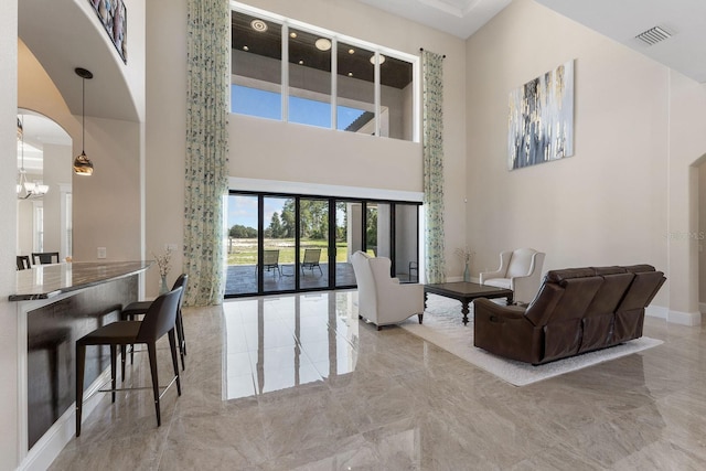 tiled living room featuring a chandelier and a high ceiling