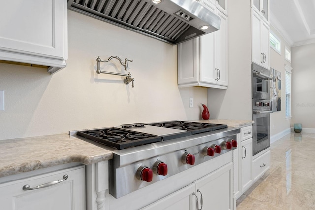 kitchen featuring light tile patterned flooring, white cabinetry, stainless steel gas stovetop, premium range hood, and ornamental molding