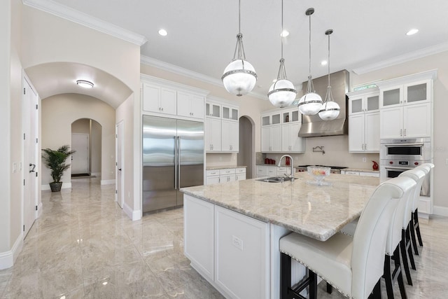 kitchen featuring stainless steel appliances, hanging light fixtures, white cabinets, sink, and a large island with sink