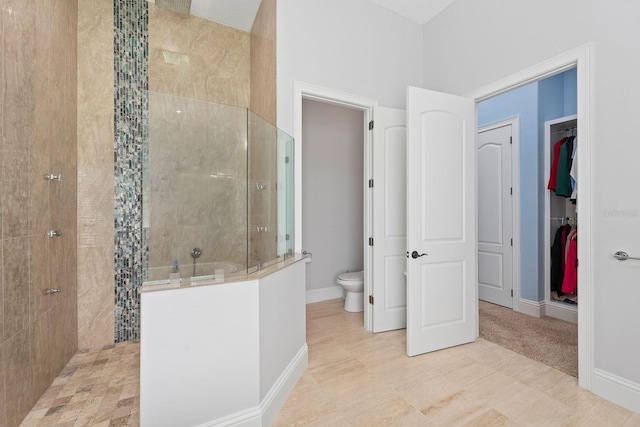 bathroom featuring tile patterned flooring, toilet, and tiled shower