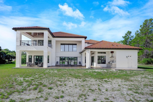 back of house with a balcony, a yard, and a patio area