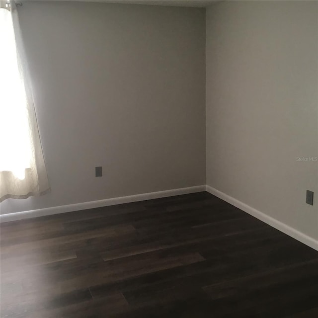 empty room with dark hardwood / wood-style flooring