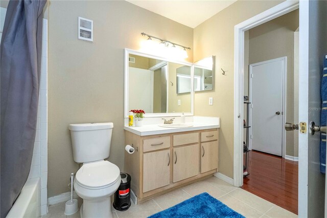 full bathroom with hardwood / wood-style floors, shower / bath combo with shower curtain, toilet, and vanity