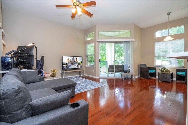 living room with ceiling fan, a towering ceiling, and wood-type flooring