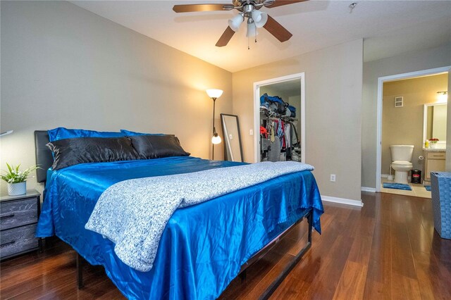 bedroom featuring a walk in closet, ensuite bath, a closet, ceiling fan, and dark tile floors