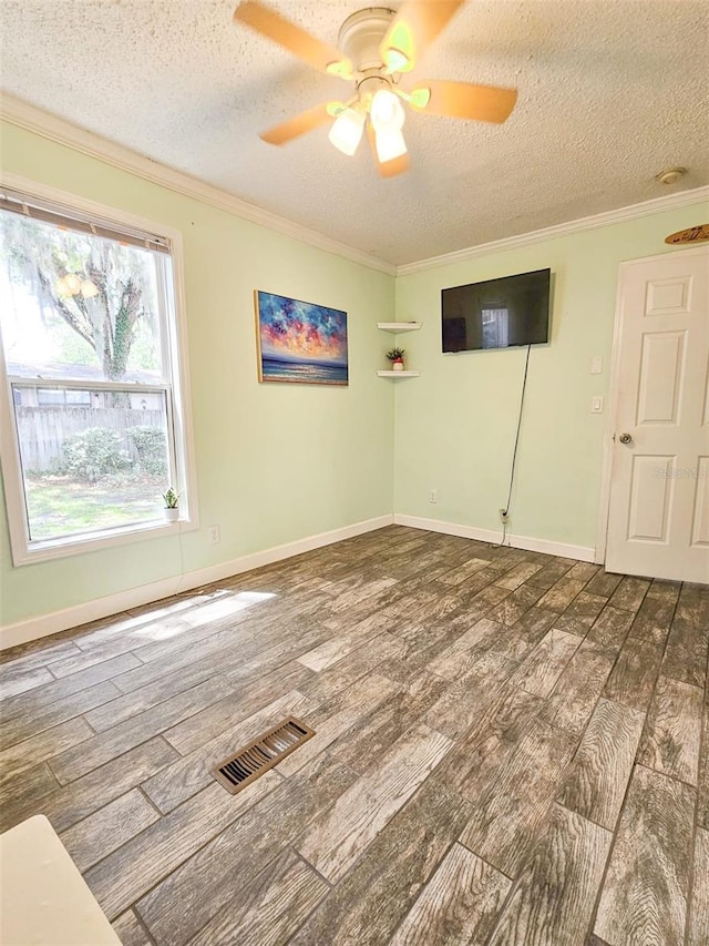 spare room featuring ceiling fan, ornamental molding, a textured ceiling, and dark wood-type flooring