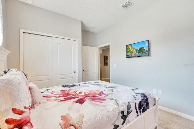 carpeted bedroom with baseboards, a textured ceiling, visible vents, and a closet