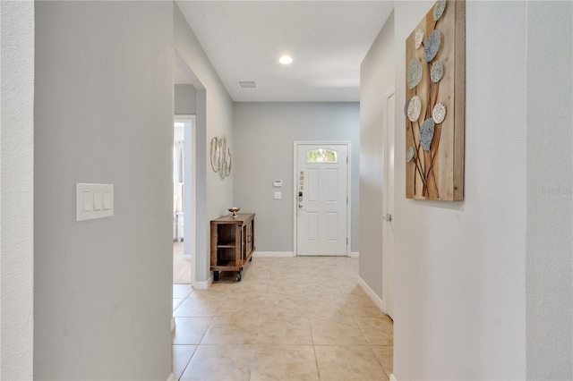 corridor with visible vents, baseboards, and light tile patterned flooring