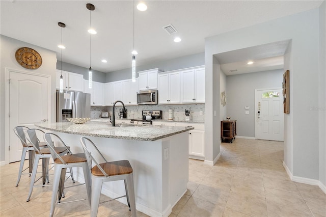 kitchen with stainless steel appliances, light stone countertops, visible vents, and tasteful backsplash