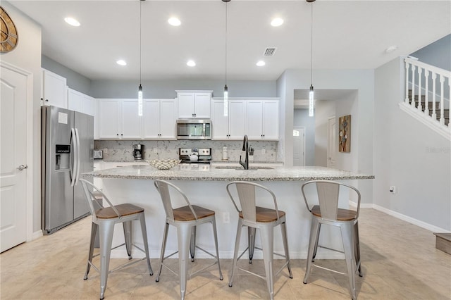 kitchen with backsplash, hanging light fixtures, appliances with stainless steel finishes, sink, and light tile floors