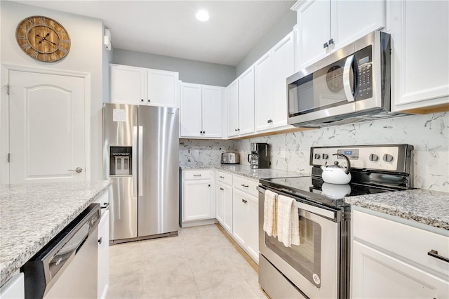 kitchen with stainless steel appliances, white cabinets, backsplash, and light tile floors