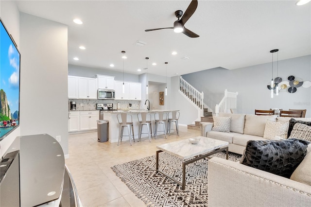 living room featuring light tile patterned floors, recessed lighting, visible vents, stairway, and ceiling fan with notable chandelier