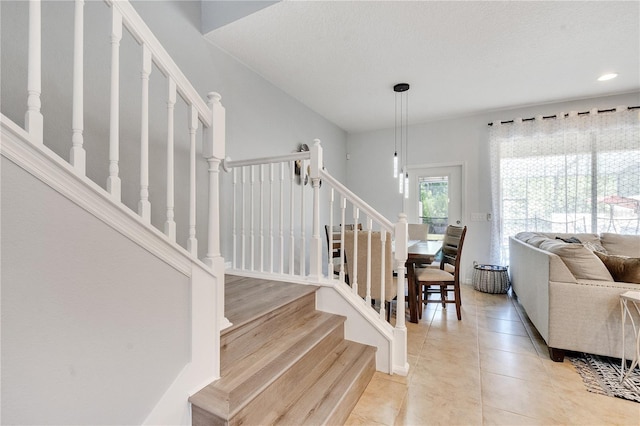 staircase with a textured ceiling and tile patterned floors