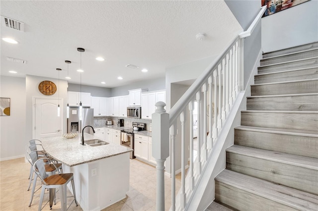 kitchen with stainless steel appliances, a sink, visible vents, and white cabinetry