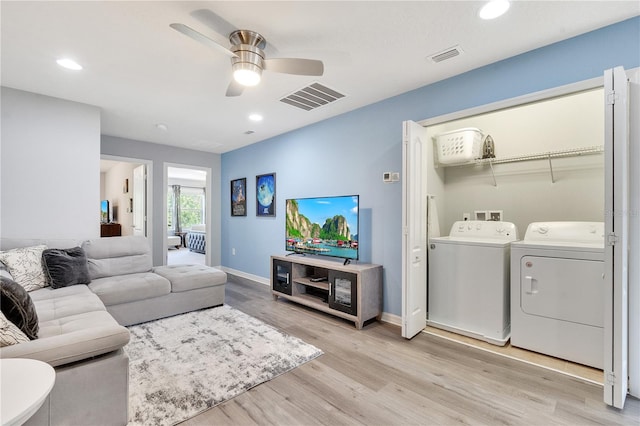 living room featuring washer and dryer, light hardwood / wood-style floors, and ceiling fan