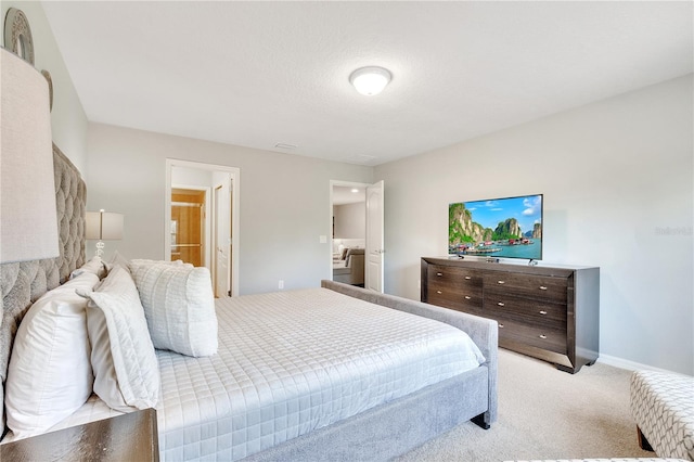 bedroom with ensuite bath, carpet flooring, and baseboards