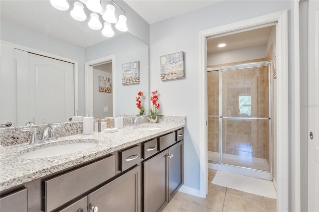 bathroom featuring vanity with extensive cabinet space, dual sinks, tile floors, and a shower with door