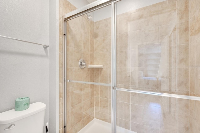 full bathroom with a stall shower, a textured wall, and toilet