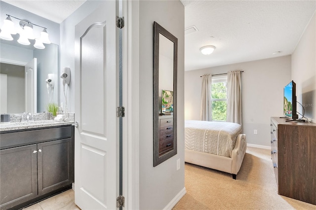 interior space featuring baseboards, vanity, ensuite bath, and a textured ceiling