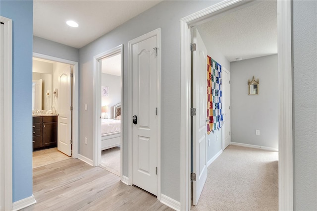 hallway with a textured ceiling and light wood-type flooring