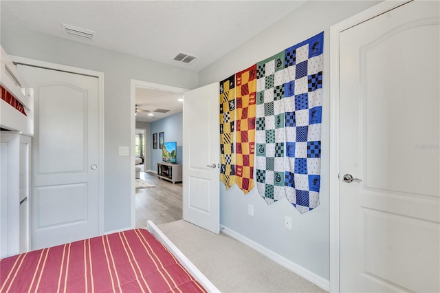 unfurnished bedroom featuring visible vents, a textured ceiling, baseboards, and light wood finished floors