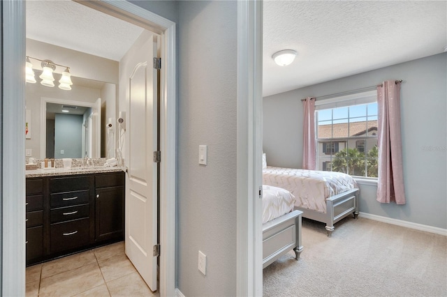 bedroom with light carpet, a textured ceiling, and ensuite bath