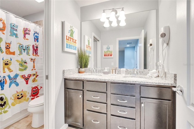 bathroom featuring tile flooring, oversized vanity, dual sinks, and toilet