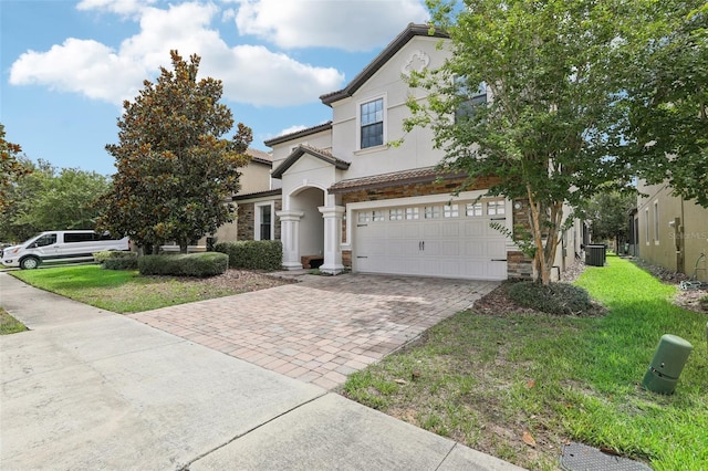 view of front of property with a front yard, a garage, and central AC