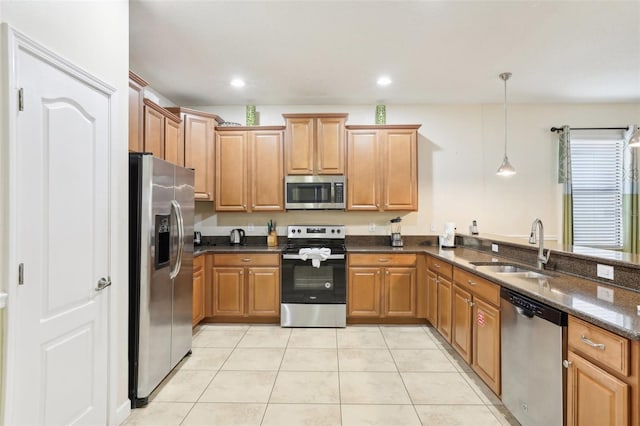 kitchen featuring dark stone countertops, sink, hanging light fixtures, stainless steel appliances, and light tile patterned floors