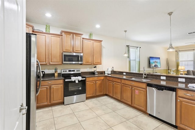 kitchen with sink, pendant lighting, appliances with stainless steel finishes, and dark stone countertops