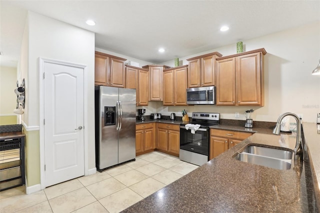 kitchen with appliances with stainless steel finishes, sink, dark stone countertops, and light tile patterned flooring