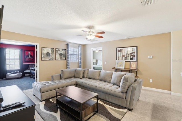 living room with ceiling fan, light colored carpet, and a textured ceiling