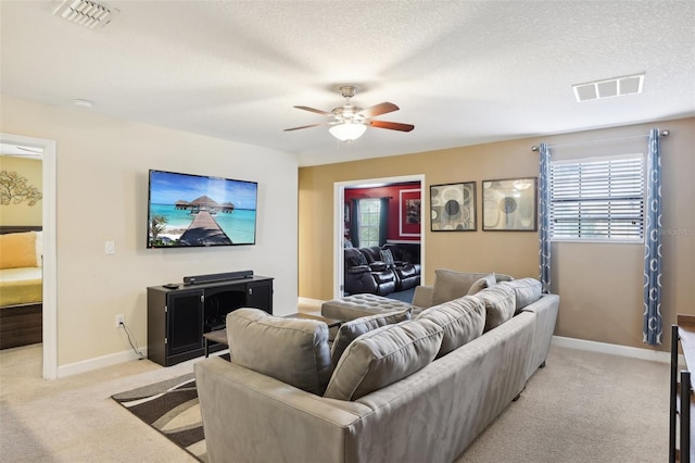 living room with ceiling fan, light colored carpet, and a textured ceiling