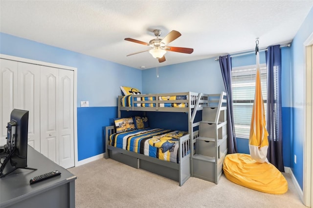 carpeted bedroom featuring ceiling fan, a textured ceiling, and a closet