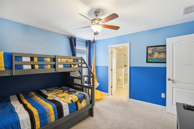 bedroom with ensuite bathroom, light colored carpet, ceiling fan, and a textured ceiling