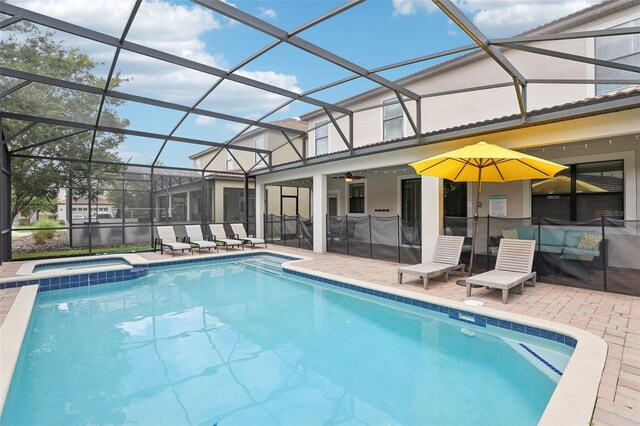 view of swimming pool featuring ceiling fan, glass enclosure, a patio area, and an in ground hot tub